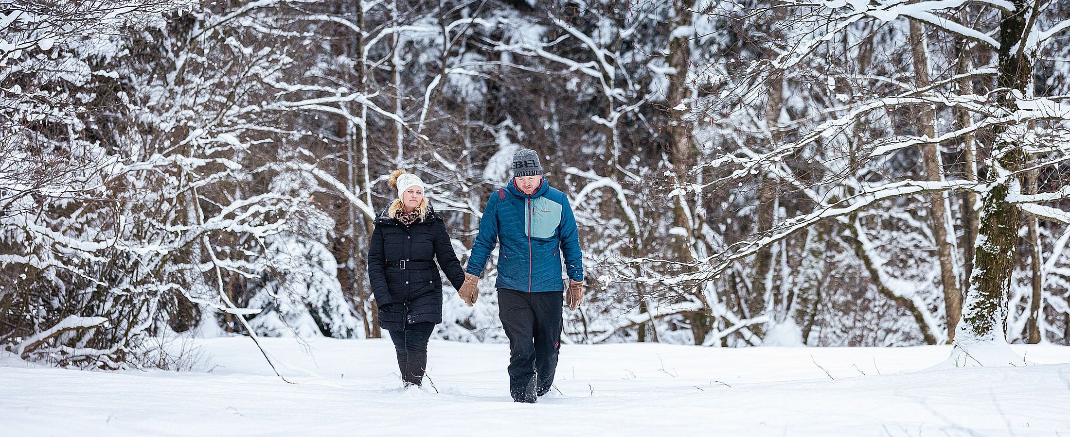 Paar beim Winterspaziergang in einem verschneiten Wald