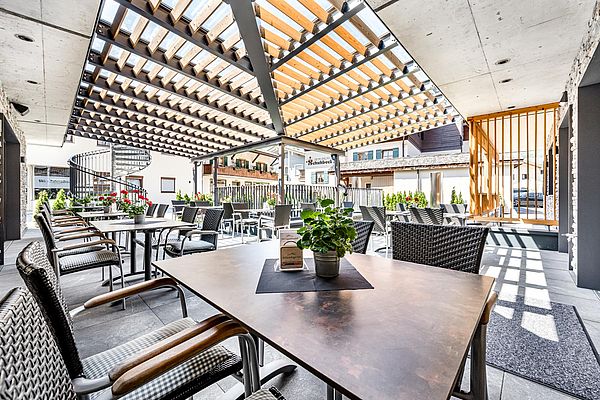 Moderne Terrasse mit stilvollen Sitzmöbeln und Holzpergola im Ruhpoldinger Hof